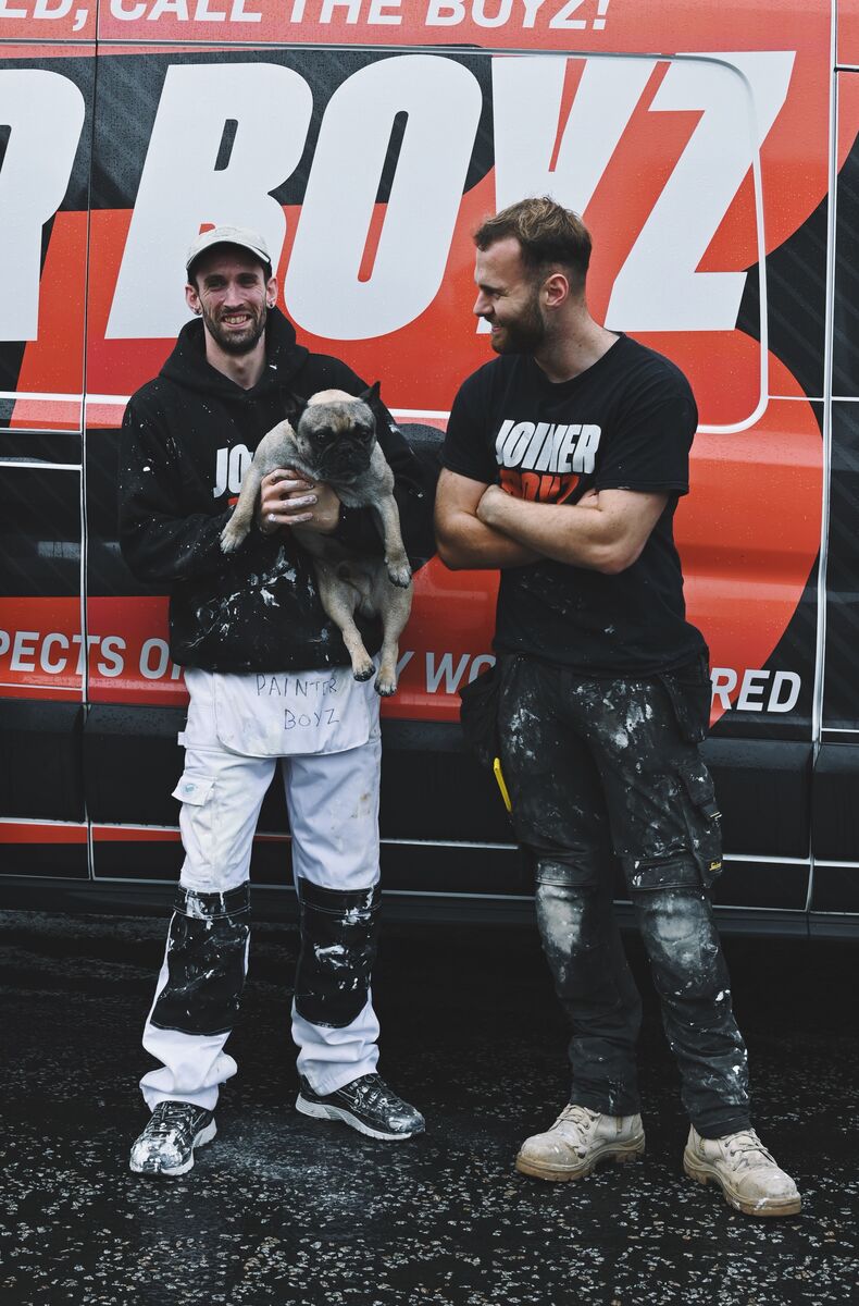 Two of the Joiner Boyz, one holding a pug, in front of the van